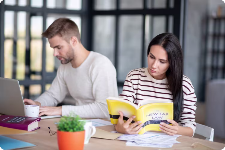 Two people researching staff pay by a desk